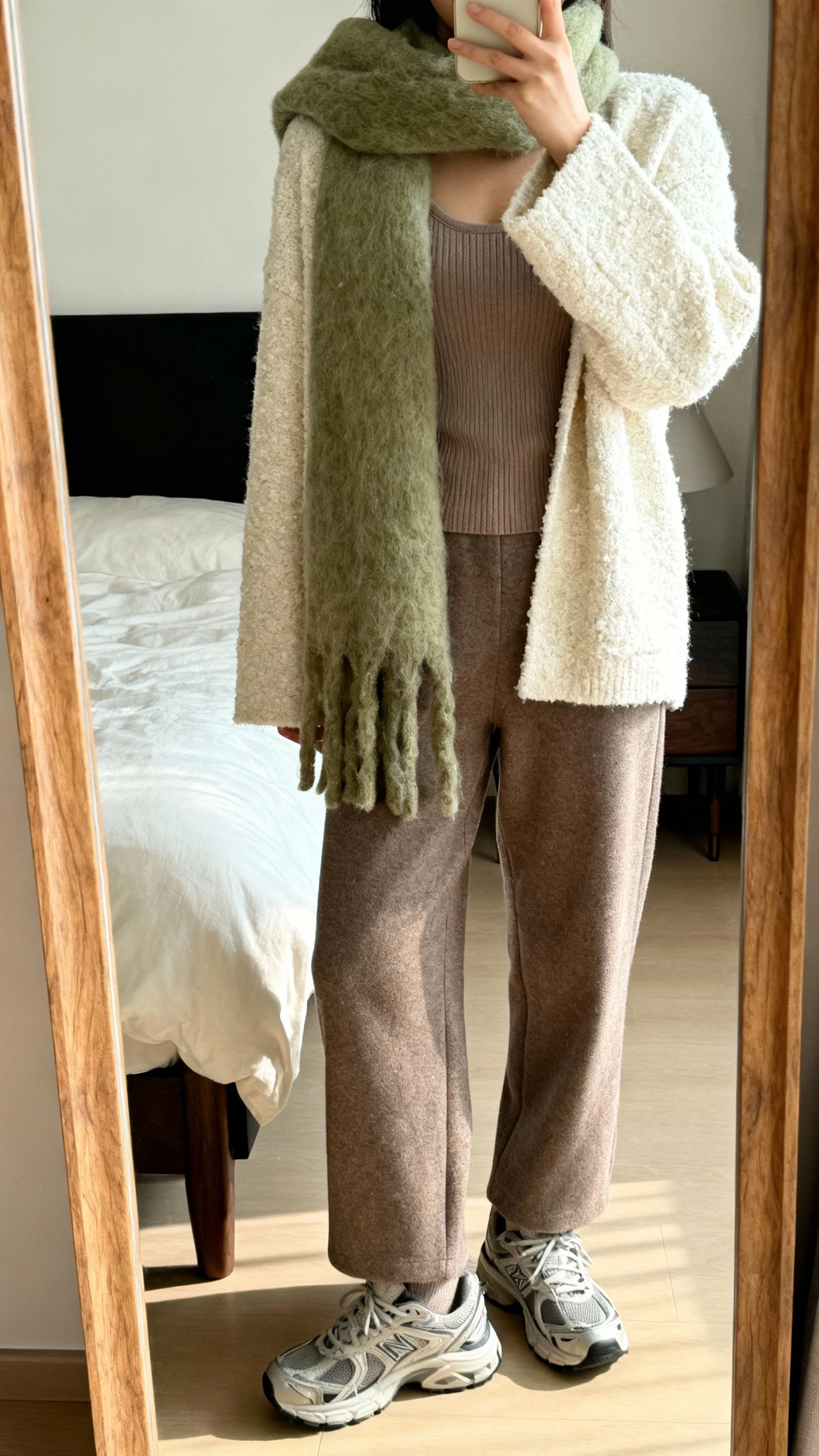 iPhone mirror selfie of a woman mixing textures: bouclé cardigan (ivory), ribbed knit tank (taupe), fuzzy mohair scarf (sage), relaxed wool trousers, chunky sneakers, face not visible, bedroom full-length mirror, soft morning light, natural iPhone photo.