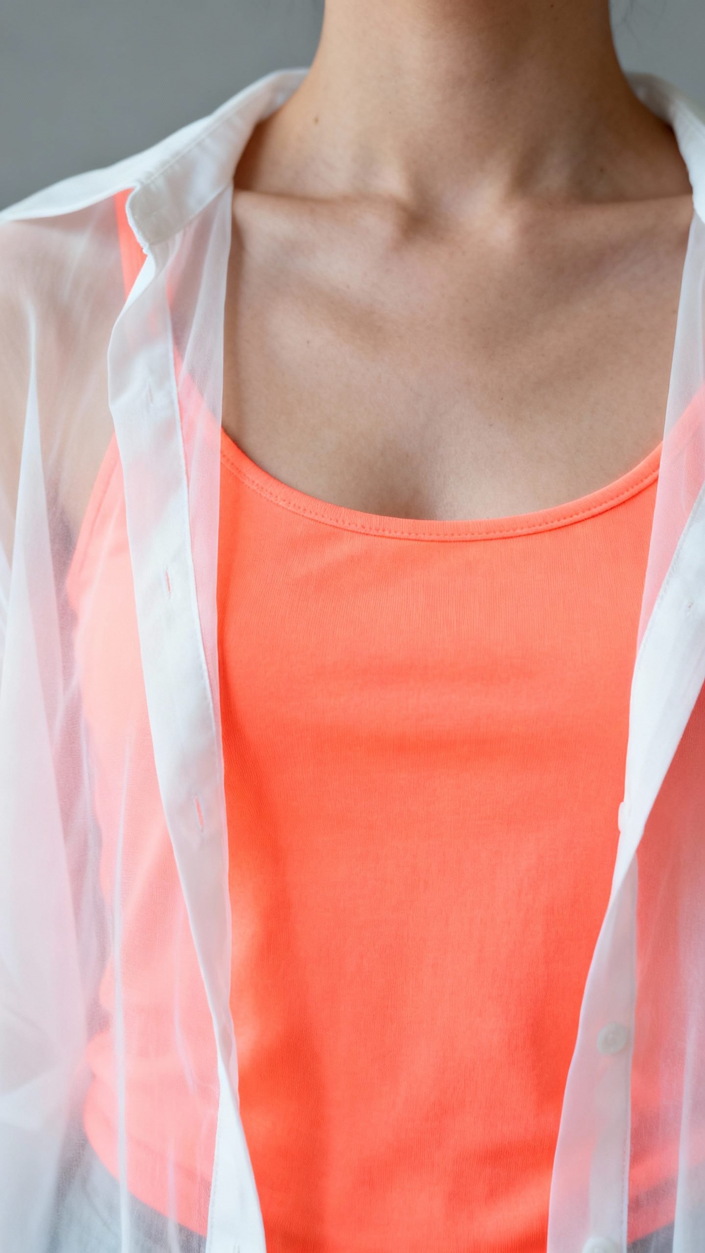 Neon tangerine tank under sheer white blouse, studio lighting