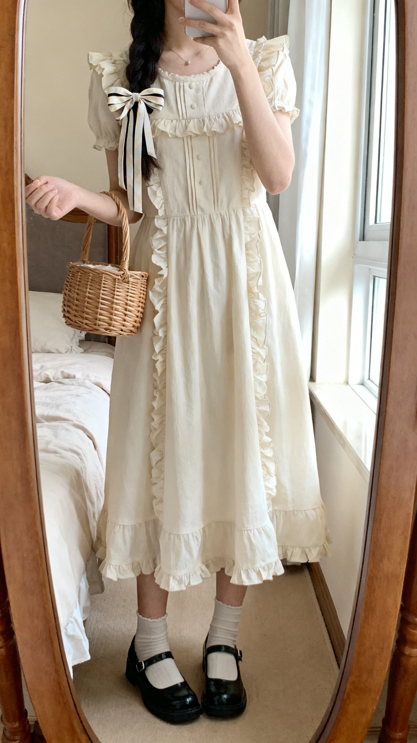 iPhone mirror selfie of a woman wearing a cottagecore babydoll dress with ruffle details, Mary Jane flats, a ribbon hair bow, and a small basket bag, face not visible, cropped at neck, bedroom mirror, soft window light, iPhone photo quality.