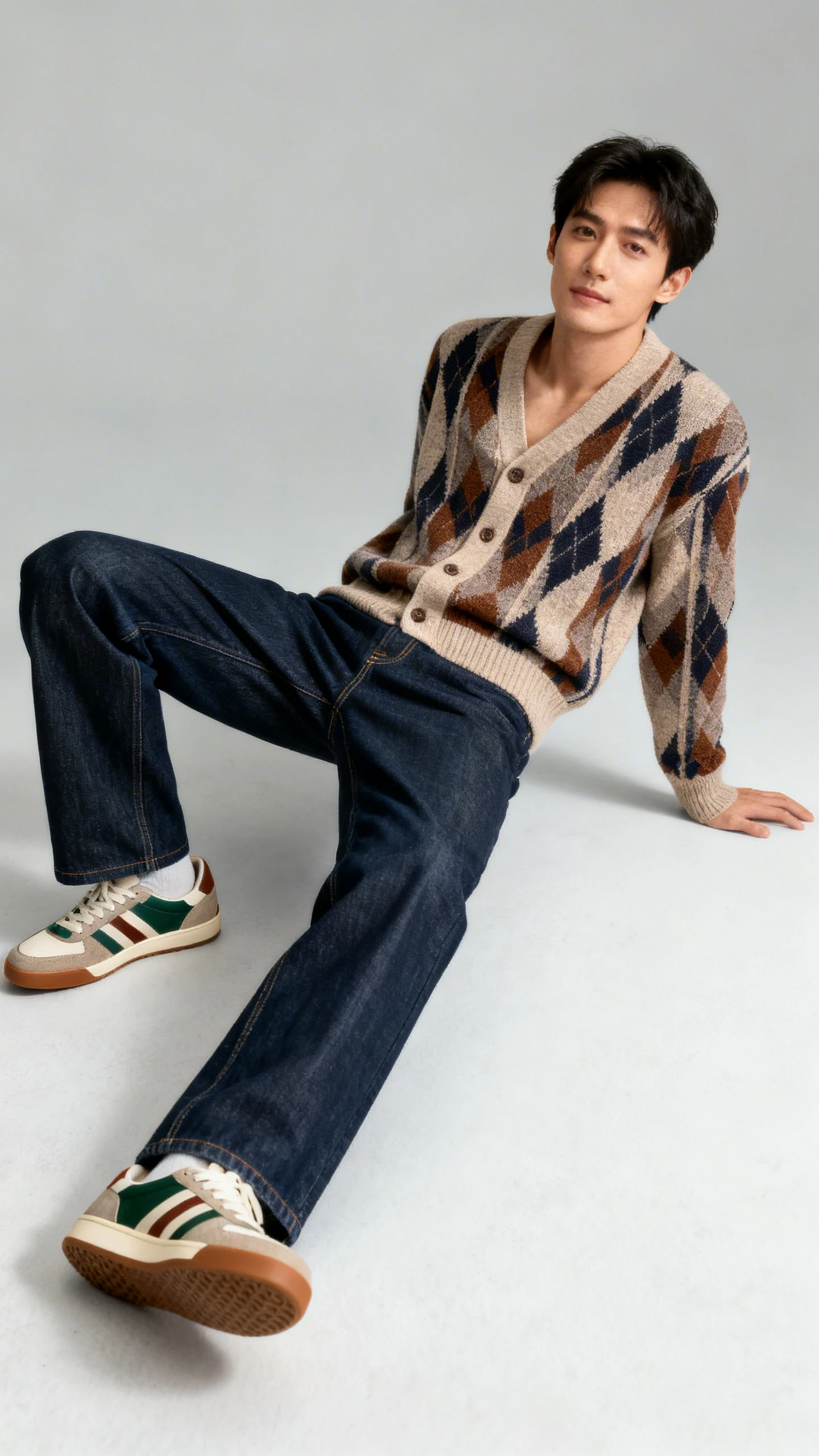 Studio fashion image of a man in a retro cardigan with straight-leg denim and vintage-style runners, light gray background, soft studio lighting, natural lean, clean composition, high quality.