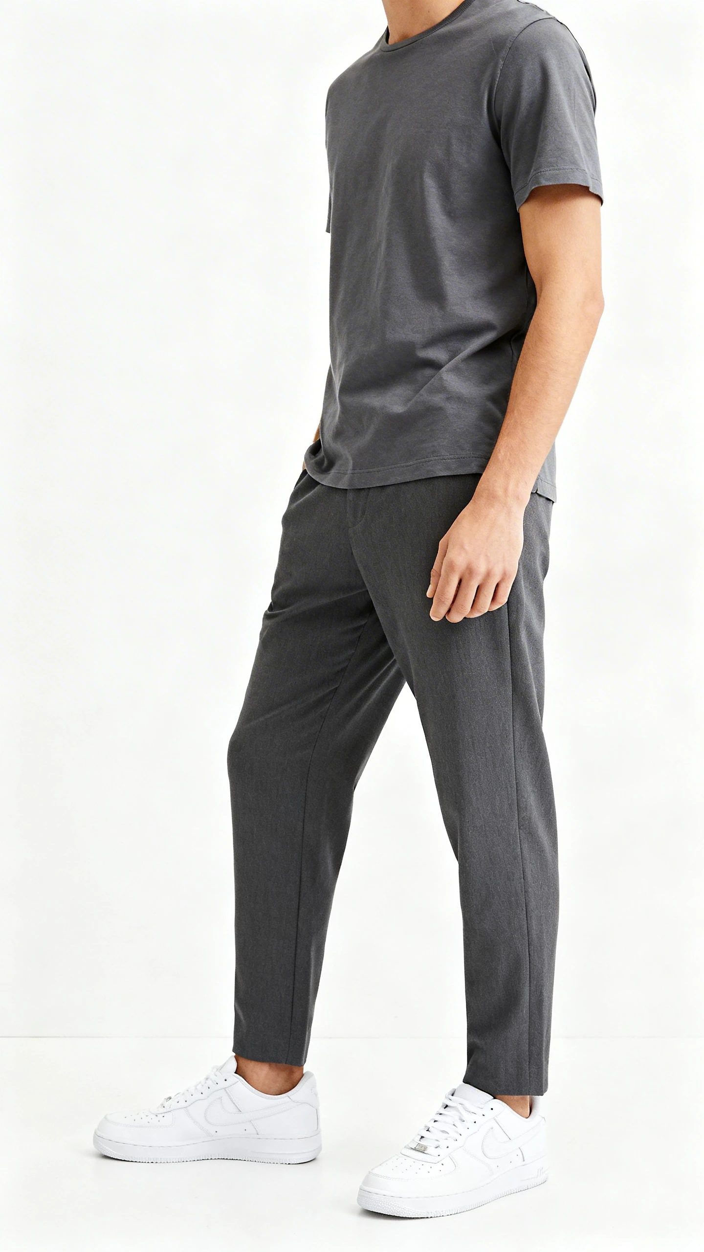 Studio photo of a man in a monochrome slate-on-slate look—slate tee and slate trousers—with a pop of white sneakers, white background, soft lighting, three-quarter angle, clean composition, magazine-quality.